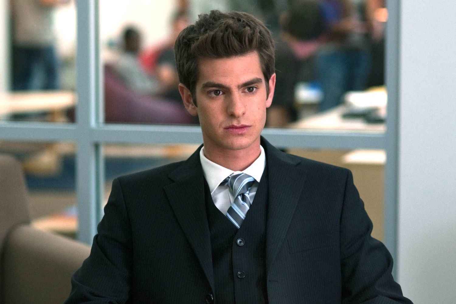 A suited man in an office setting related to Andrew Garfield's 'The Social Network' sequel news