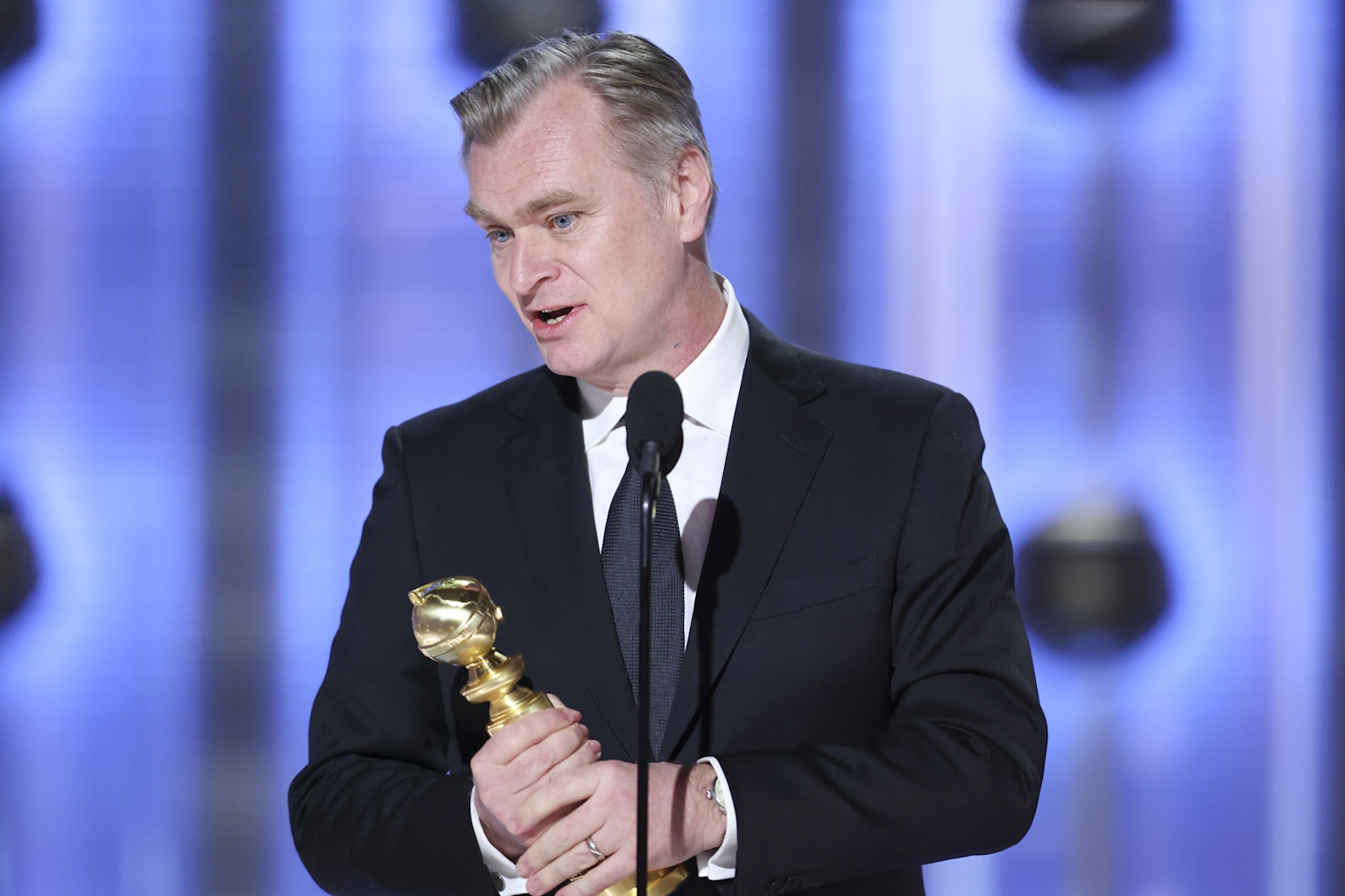 Christopher Nolan holding a Golden Globe award, celebrating his achievement as Directors Guild of America president in 2025
