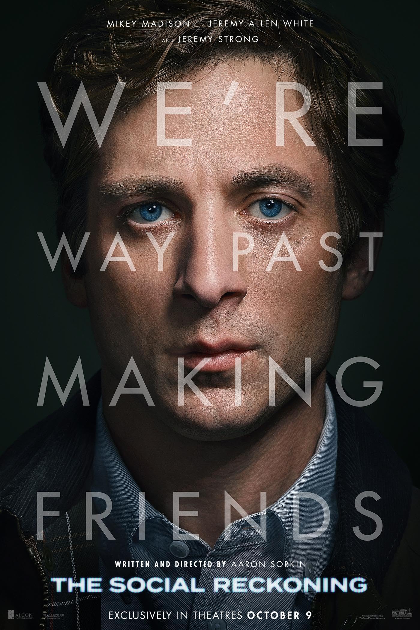 Close-up portrait of a man with blue eyes and light brown hair against a dark background, with large translucent title text across the face promoting a film poster. Includes lines like 'Written and Directed by Aaron Sorkin' and 'The Social Reckoning' visible at the bottom.