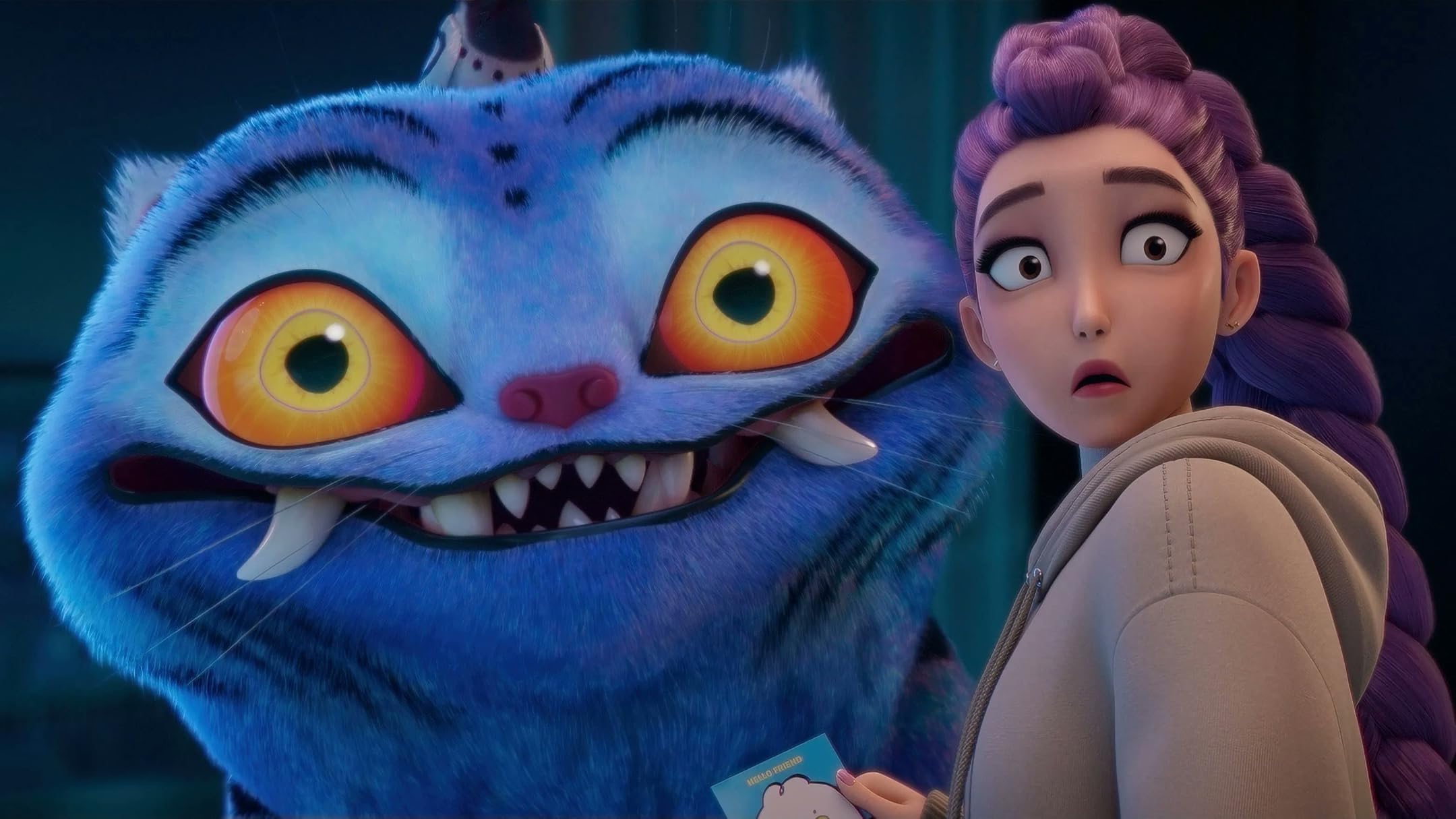 Blue fuzzy monster with large orange eyes leans toward a surprised young woman with purple braided hair. They appear indoors and are holding a small card together.