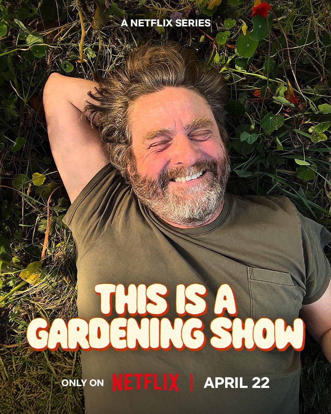 Smiling man lying in garden foliage, wearing a green shirt that reads 'THIS IS A GARDENING SHOW'—Netflix poster. (informational)