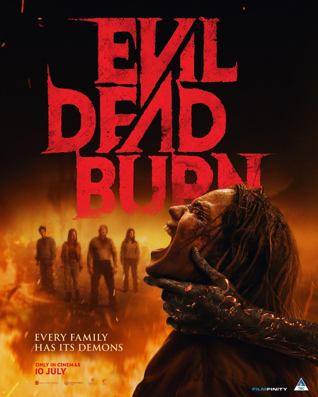 Poster for Evil Dead Rise: a screaming woman with a demonic, clawed hand around her neck against a fiery background and a family silhouette in the distance.
