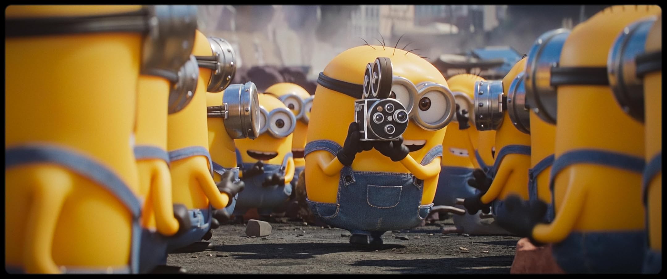 A group of yellow Minions in blue overalls crowd around as one holds a vintage film camera to film or photograph the scene.