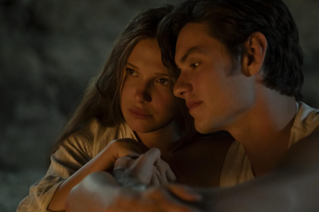 Two people cuddled close in a dimly lit setting, their faces near each other and a calm, intimate mood.